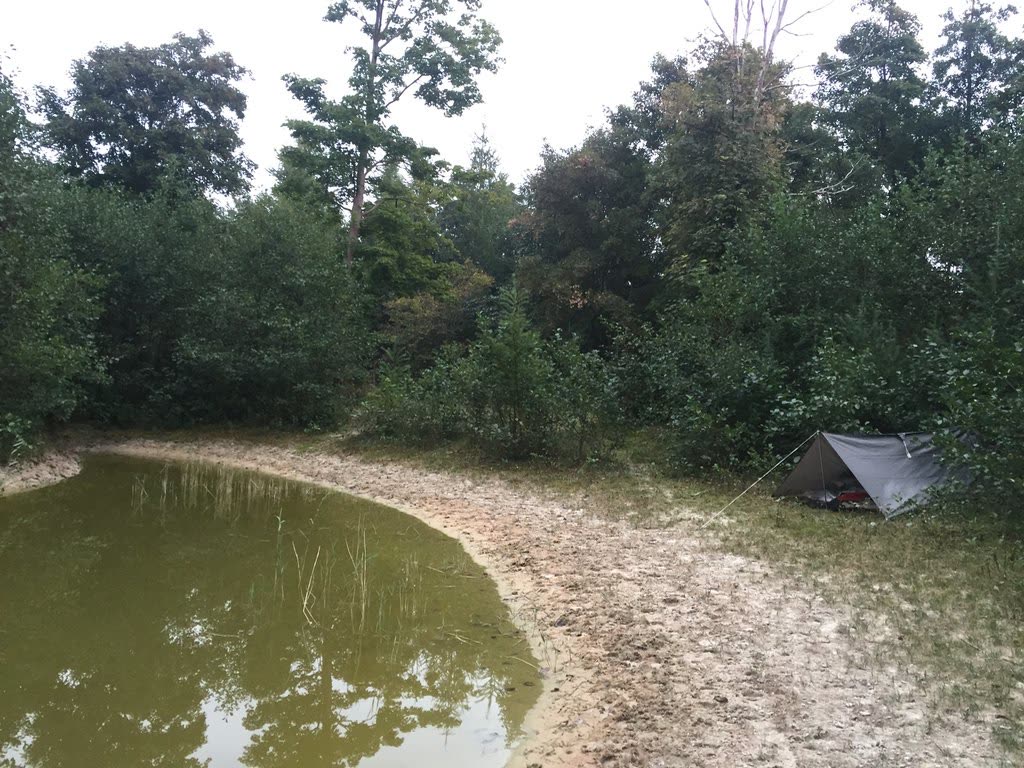 Een klein tentje aan de oever van een ven tussen de bomen